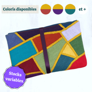 Image carrée sur fond clair. Elle est centrée sur une pochette à livre multicolore. Elle est réalisée à partir de chutes de lins colorés, brodés ensembles avec du fil doré. Le résultat ressemble à un vitrail. La pochette se ferme grâce à un ruban en satin violet que l'on enroule autour. Dans le coin en bas à gauche, il y a une vignette violette avec noté "stocks variables".
