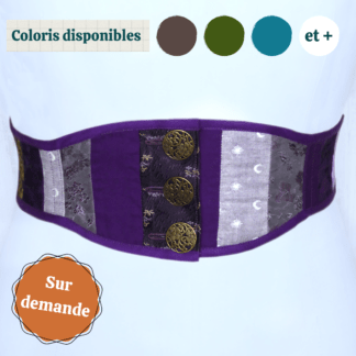 Plan rapproché sur le devant d'une ceinture corsetée, portée sur un mannequin blanc qui se fond un peu dans l'arrière plan. La ceinture est composée d'un patchwork de tissus dans les tons violets, et se ferme au milieu grâce à 3 boutons en laiton vieil or. En haut de l'image se trouvent des vignettes indiquant les coloris disponibles, et en bas à gauche se trouve un macaron indiquant "sur demande".